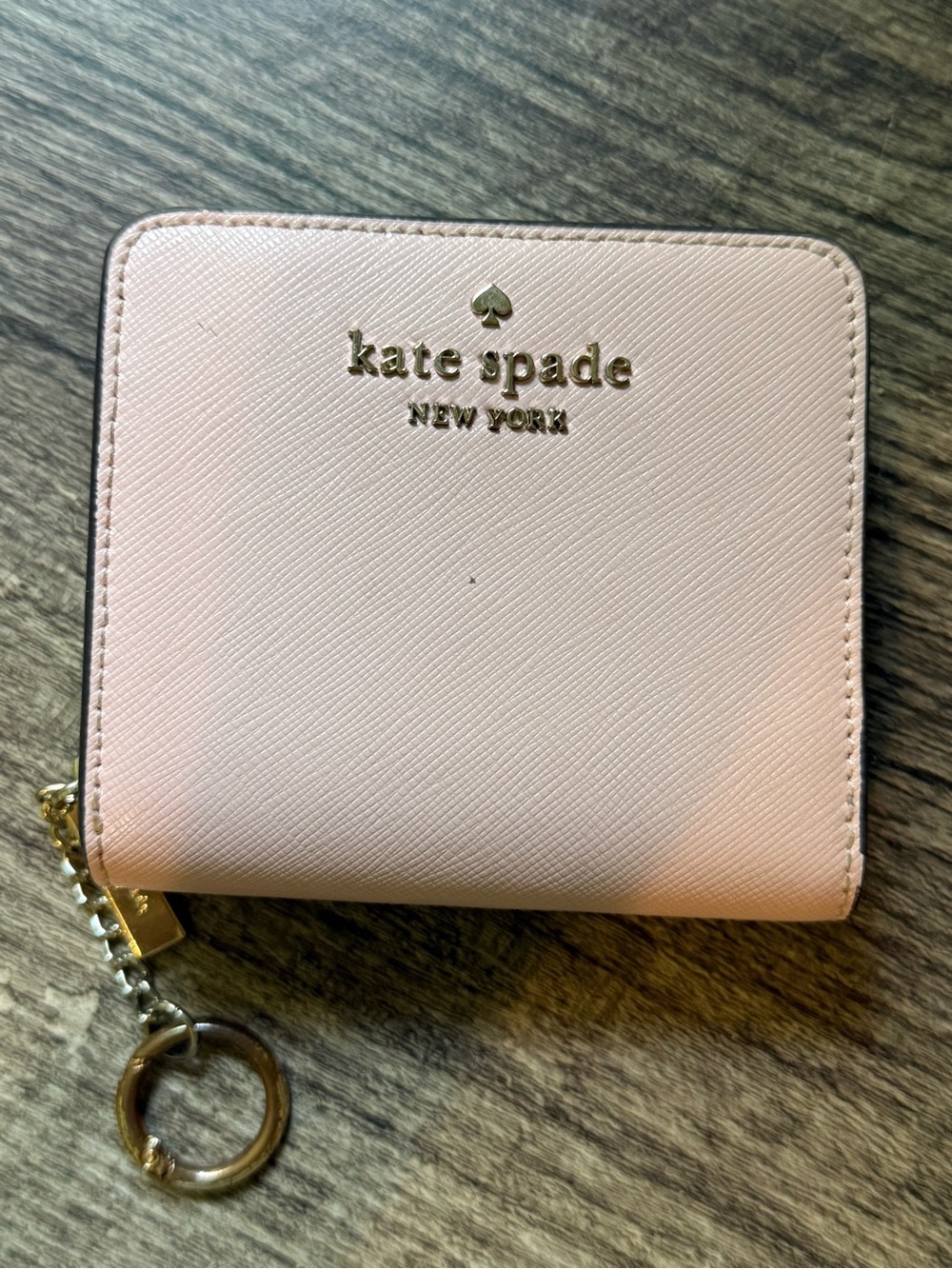 This is a light pink Kate Spade Saffiano leather bifold wallet. Smoke free home